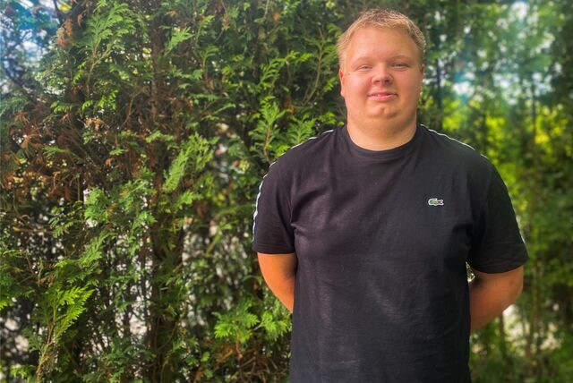 Florian Heickes steht vor einer grünen Hecke.