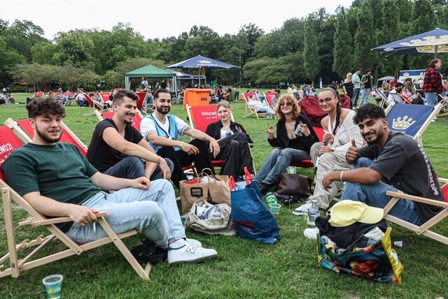 Navid (rechts) ist mit vielen Freunden zum DJ Picknick in den Fredenbaumpark gekommen. Die Gruppe macht es sich auf Liegestühlen bequem.