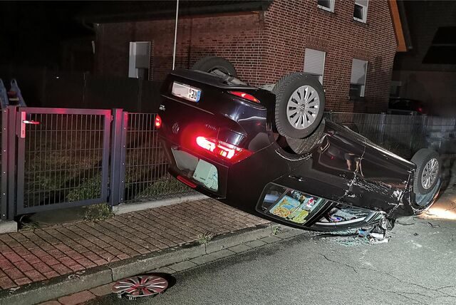 Ein Auto liegt auf dem Dach auf einem Gehweg.