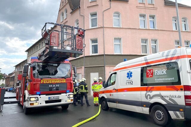 Ein Drehleiterwagen der Feuerwehr und ein Krankentransporter stehen auf einer Straße.
