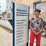 Susanne Rohn vor dem Haus der Diakonie neben einem Schild.