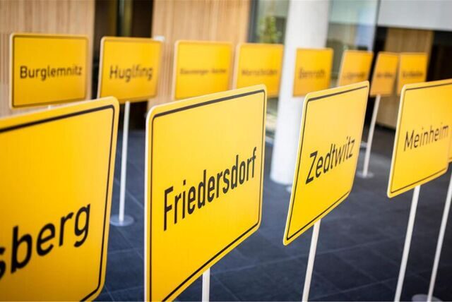 Gelbe Ortseingangsschilder stehen in einem Raum.