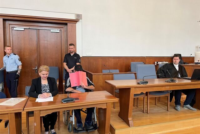 Nach einer lebensgefährlichen Bluttat in einem Pflegeheim in Hamm hat vor dem Dortmunder Schwurgericht der Mordversuch-Prozess begonnen. Angeklagt ist ein Ex-Bewohner (Mitte, Gesicht verdeckt). Links daneben: eine Dolmetscherin. Ganz rechts: Verteidiger Veit Demmig.