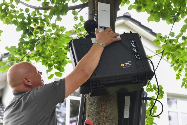 Ein Techniker installiert an einem Haus ein Schallpegelmessgerät zur Lärmbestimmung