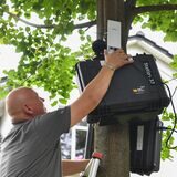 Ein Techniker installiert an einem Haus ein Schallpegelmessgerät zur Lärmbestimmung