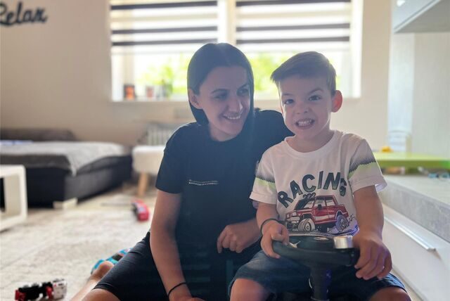 Esliona Cangollari (32) und ihr Sohn Noel Goxhaj (3) sitzen im Wohnzimmer, die Mutter auf einem Teppich, der Dreijährige auf einem Spielauto.
