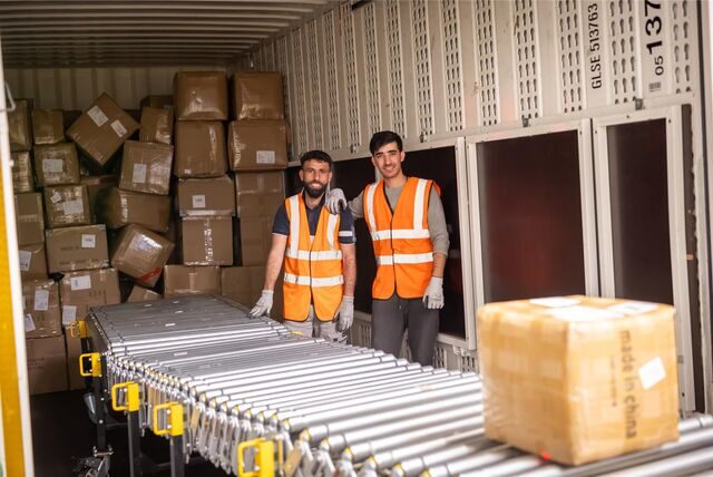 Wareneingang bei Amazon in der Nordstadt: Zwei Mitarbeiter entladen einen Lkw. Die Kartons kommen per Förderband in die Erfassung und Sortierung.