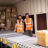 Wareneingang bei Amazon in der Nordstadt: Zwei Mitarbeiter entladen einen Lkw. Die Kartons kommen per Förderband in die Erfassung und Sortierung.