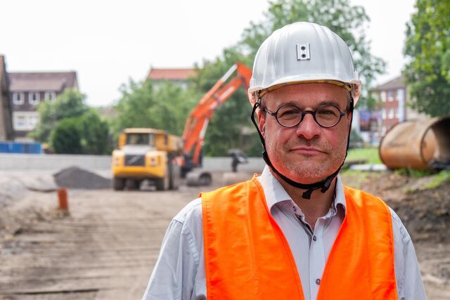 Ein Mann mit Helm steht auf einer Baustelle.