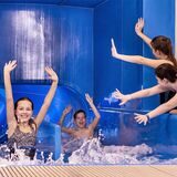 Kinder rutschen die Rutsche im Spaßbad des Copa Ca Backum hinunter und recken die Arme in die Luft.