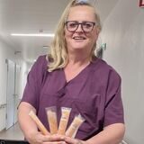 Eine Frau zeigt Wassereis vor Getränkekisten