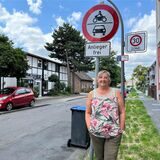 Die Recklinghäuserin Claudia Marczian steht am Eingang zur Schleusenstraße neben einem „Anlieger frei“- und einem „30er-Zone“-Schild.