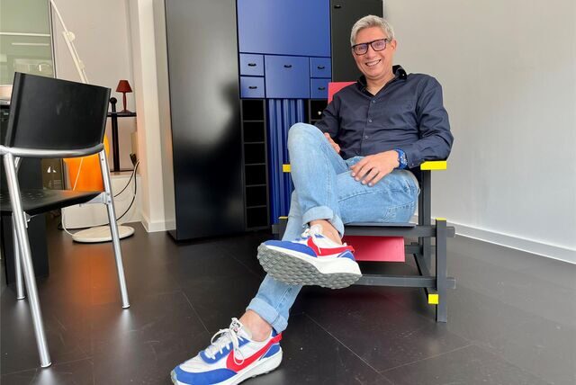 Frank Stötzer hat sich auf einen Stuhl des Designers Gerrit T. Rietveld gesetzt. Der wurde vor zirka 100 Jahren entworfen. Das Modell ist ein Nachbau aus den 1980er Jahren. Im Hintergrund ist ein Barschrank zu sehen.