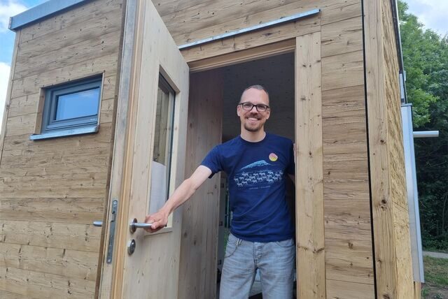Ein Mann steht in der Tür eines Holzhauses