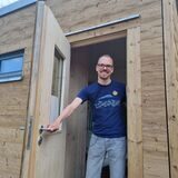 Ein Mann steht in der Tür eines Holzhauses