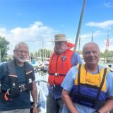 Drei Männer stehen vor Segelbooten