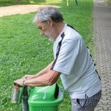 Ein Mann befestigt eine silberne Dose hinter einem Mülleimer.