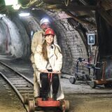 Bergmann Marcel Grigull und Reporterin Janka Hardenacke sitzen auf einem Grubenfahrrad im Trainingsbergwerk Recklinghausen.