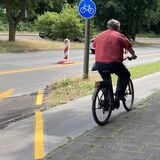 Ein Mann  fährt auf einem Fahrradweg.