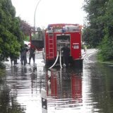 Feuerwehrwagen steht auf einer überfluteten Straße
