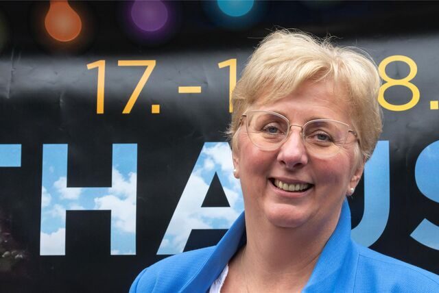 Cordula Brink steht vor dem Veranstaltungsbanner zum Rathausfest im Licht.