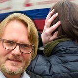 Ein vorbeifahrender Lkw kann sehr laut sein. Eine Frau hält sich die Ohren zu.