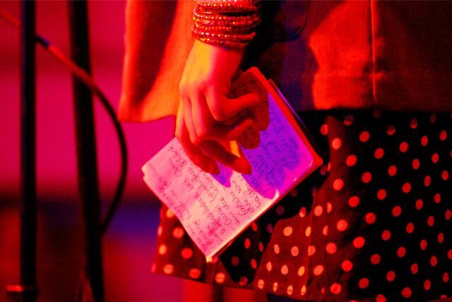 Eine Autorin hält bei einem Poetry Slam ihre Notizen in der Hand