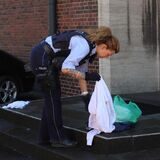 Eine Polizistin hebt Kleidungsstücke an einem Tatort in Dortmund auf.