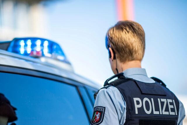 Eine Polizistin steht vor einem Streifenwagen (Symbolbild).