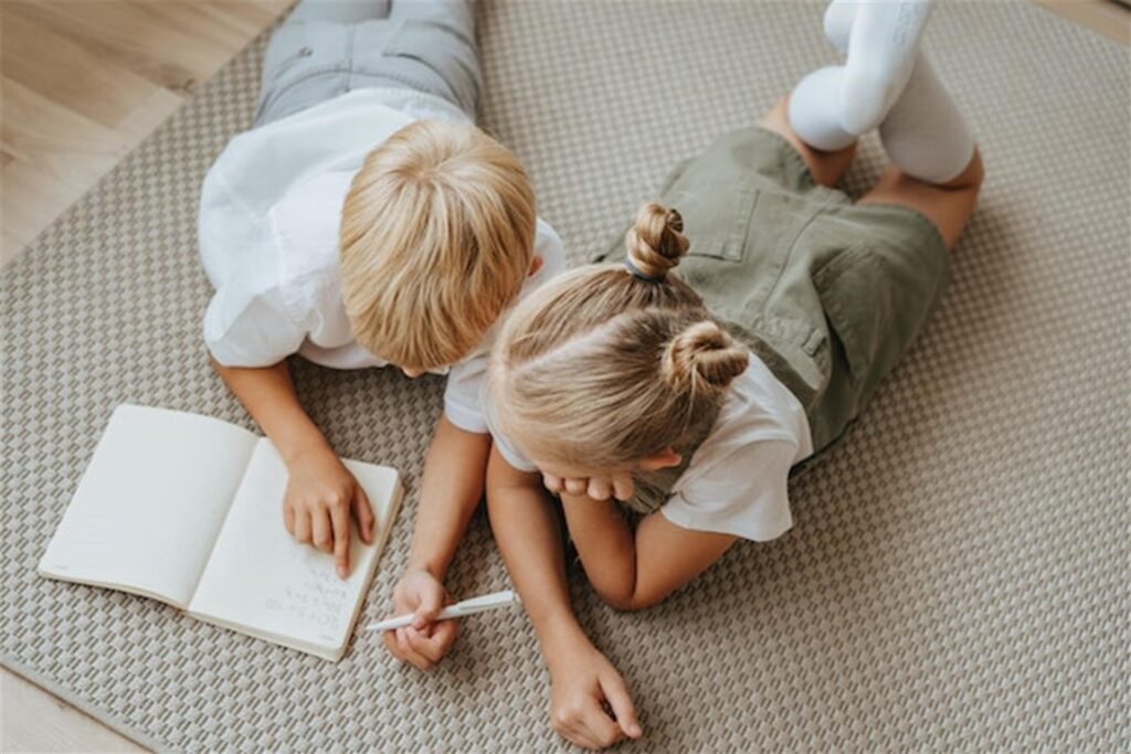 zwei kinder lesen und schreiben auf einem teppich zwei kinder lesen und schreiben auf einem teppich
