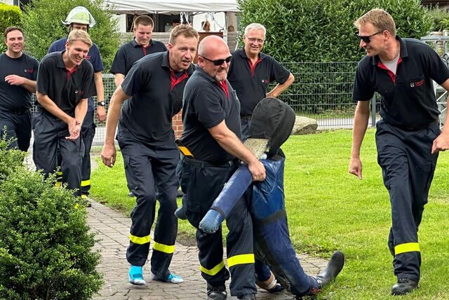 Feuerwehmann schleppt Puppe, andere schauen zu