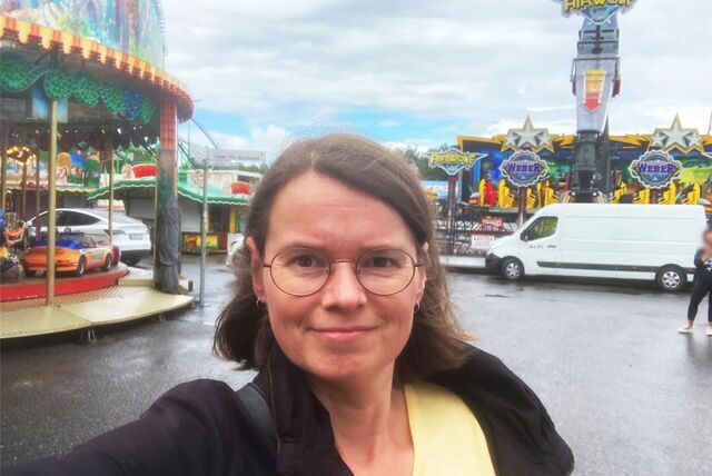 HA-Redakteurin steht auf dem Gelände der Cranger Kirmes zwischen verschiedenen Fahrgeschäften.