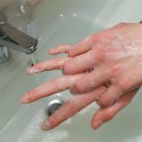 Ein Mensch beim Händewasen an einem Waschbecken.