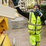 Ein Müllwerker wirft etwas in ein Müllfahrzeug