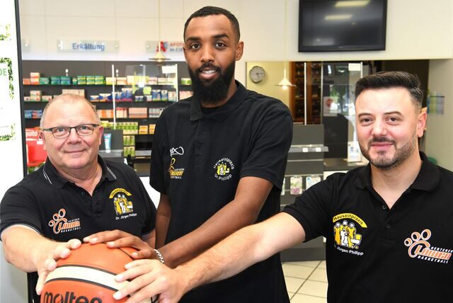 Basketball. 1. August 2023. Vorsitzender Hermann Zechel (links) und Cheftrainer Robin Singh (Rechts) präsentieren den nächsten Zugang für die Regionalliga-Saison 2023/2024, Mohamed Moe Abdiwahid (ehemals TuS HammStars).