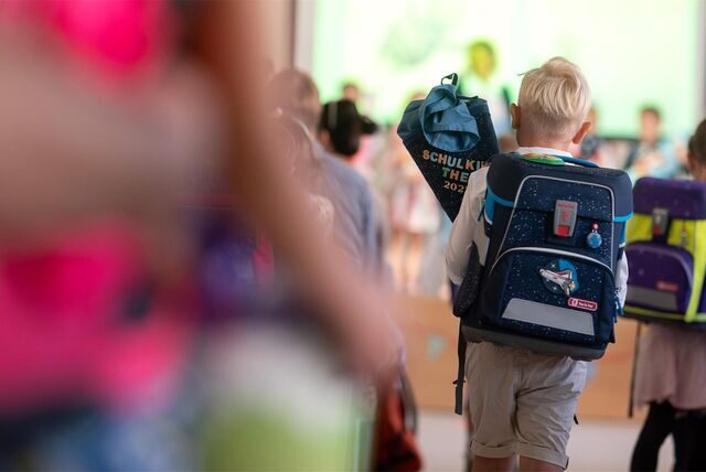 Ein Junge geht während einer Einschulungsfeier mit einer Schultüte Richtung Bühne.