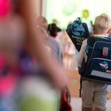 Ein Junge geht während einer Einschulungsfeier mit einer Schultüte Richtung Bühne.