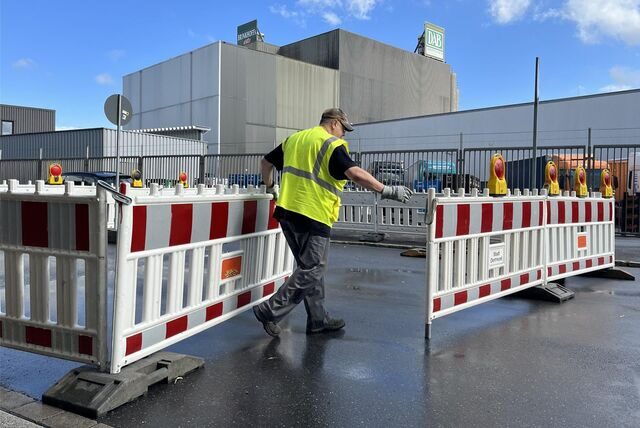 Ein Arbeiter errichtet eine Straßensperrung
