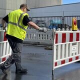 Ein Arbeiter errichtet eine Straßensperrung