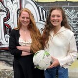 Birte Gooßes (l.) und Emely Lukasiewiecz stehen mit einem Fußball in der Hand auf dem Hof der Altstadtschmiede vor einer Graffiti-Wand,