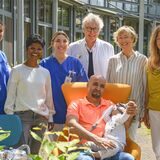 Eine Gruppe Menschen steht hinter einem Mann, der sitzt und ein Kind auf dem Schoß hat