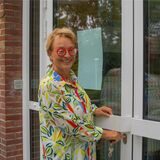 Eine Frau mit einer roten Brille schließt eine Tür ab.