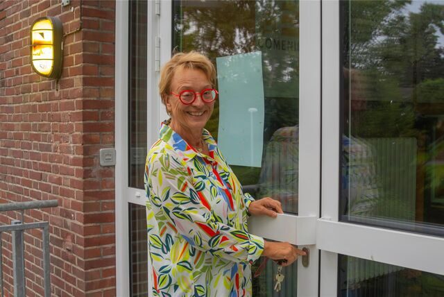 Eine Frau mit einer roten Brille schließt eine Tür ab.