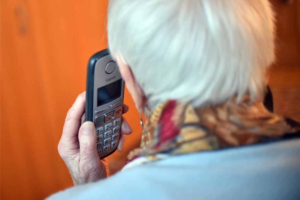 Eine Seniorin hält ein Telefon in der Hand. Eine Seniorin hält ein Telefon in der Hand.
