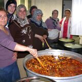 Frauen stehen an einem großen Kochtopf