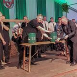 Ein Mann schlägt vor einer Gruppe Schützen ein Bierfass an.