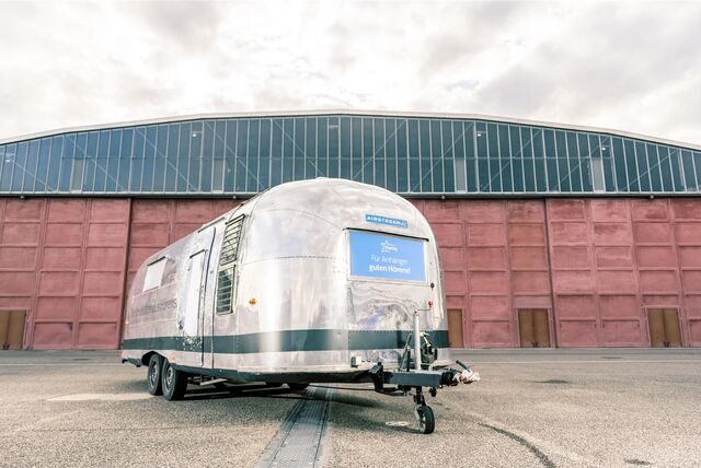 Ein metallener Trailer-Anhänger steht vor einer Industriehalle.
