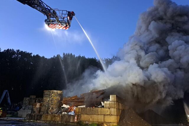 Feuerwehrleute löschen einen Brand auf einem Schrottplatz.