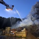 Feuerwehrleute löschen einen Brand auf einem Schrottplatz.
