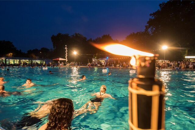 Im Parkbad Nord in Castrop-Rauxel schwimmen Menschen, während es bereits dunkel ist.